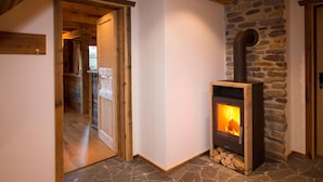 A cozy room with a stone fireplace, wooden beams, and a wooden door. - Chalet Steinbock, St. Martin am Tennengebirge (Sankt Martin am Tennengebirge)
