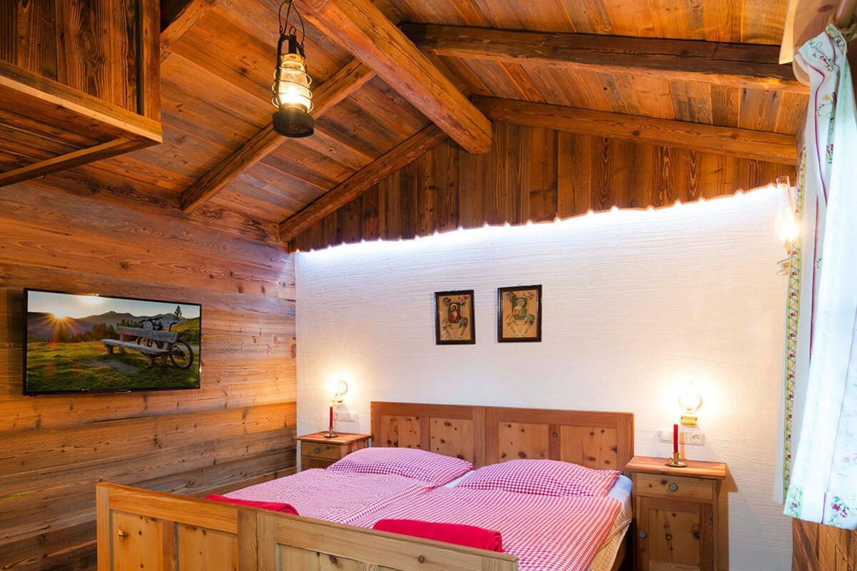 Een houten slaapkamer met een bed, nachtkastjes en een plafondlamp.