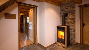 A cozy room with a stone fireplace, wooden beams, and a wooden door. - Chalet Steinbock, St. Martin am Tennengebirge (Sankt Martin am Tennengebirge)