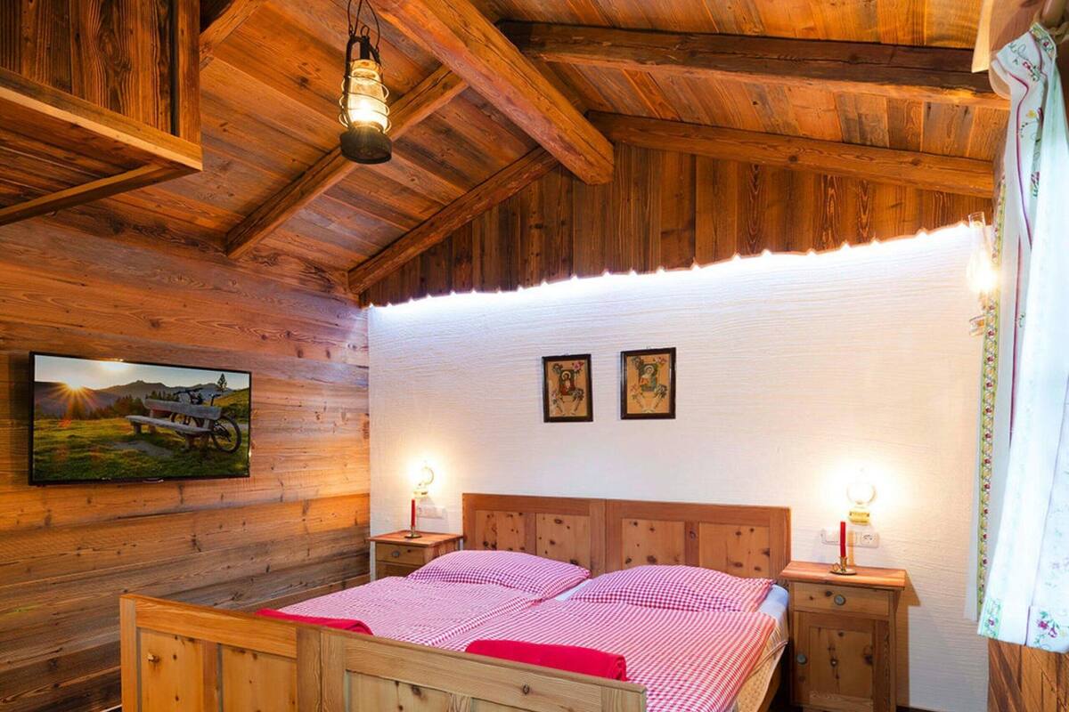 Une chambre dans une cabane en bois, avec un lit, des tables de chevet et un luminaire au plafond.