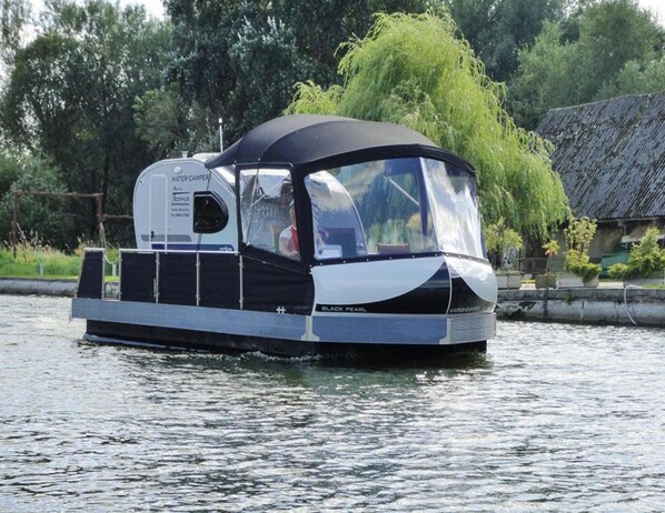 A watercraft with a covered cabin, a water-camper, and the name "BLACK PEARL" on the side.