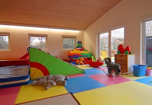 A playroom with a foam playpen, a stack of colorful building blocks, and a variety of toys. - Holiday Resort in the Muritz National Park, Mirow (Mirow)