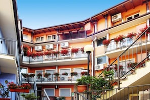 A multi-story building with balconies, air conditioning units, and potted plants.