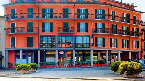 A multi-story building with balconies, a ground-level entrance, and potted plants. - Apartment in the Residence dei Fiori, Baveno (Baveno)