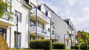 A modern multi-story residential building with balconies, large windows, and a well-maintained lawn. - Apartment in Boltenhagen Near the sea (Boltenhagen)