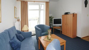 A living room with a blue sofa, a wooden coffee table, a television, and a cabinet. - Apartment in Boltenhagen Near the sea (Boltenhagen)