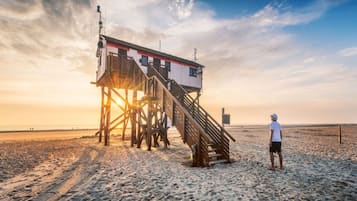 Torre de salvavidas con escalera en una playa arenosa al atardecer.