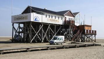 Un edificio con un letrero que dice "Digi-Sekretis" sobre una estructura de madera frente a una playa.