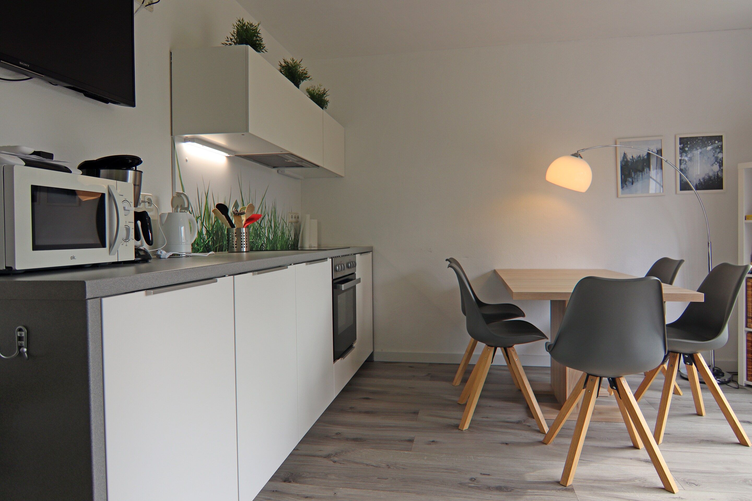 A modern kitchen with white cabinetry, a microwave, a stove, and a dining area with a table and chairs.