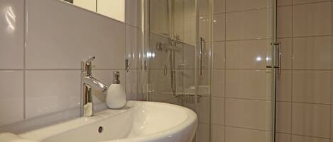 A bathroom with a white sink, a glass shower enclosure, and a mirror.