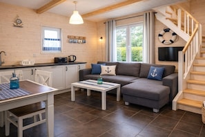 Een gezellige woonkamer met een bank, een salontafel, een eettafel en een keukenhoek.