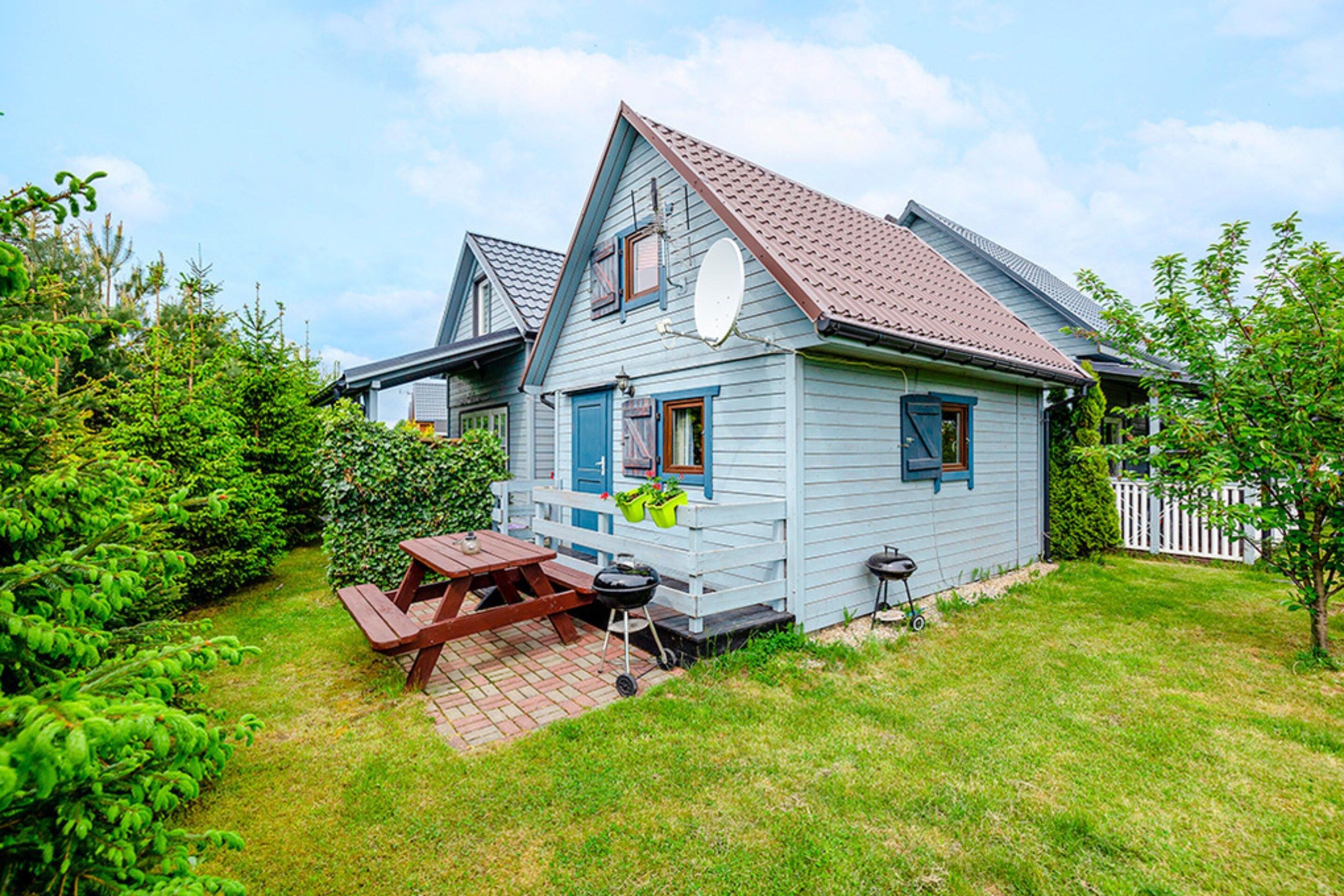 A two-story house with a sloped roof, a satellite dish, and a wooden deck with a picnic table.