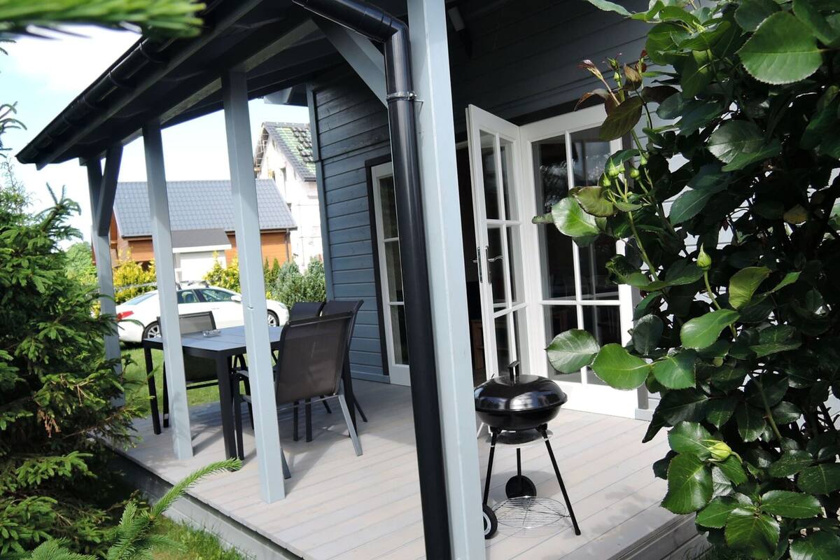 An outdoor patio with a table and chairs, a barbecue grill, and a covered area with a view of the neighborhood.