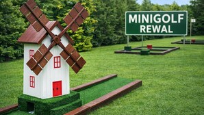 A model windmill with a red door, a sign reading 'MINIGOLF REWAL,' and a green field with a clear sky. - Holiday Home in a Holiday Park Rewal at 600 m From the sea (Rewal)