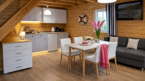 Een gezellig chalet interieur met een eethoek, keuken en woonruimte, met houten wanden en een slaapverdieping.