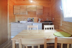 A wooden interior with a kitchen area, including cabinets, a sink, and a dining table with chairs. - Holiday Home in a Holiday Park Rewal at 600 m From the sea (Rewal)