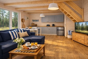 Een gezellig chalet interieur met een zithoek, kitchenette en een eethoek met ontbijtartikelen.