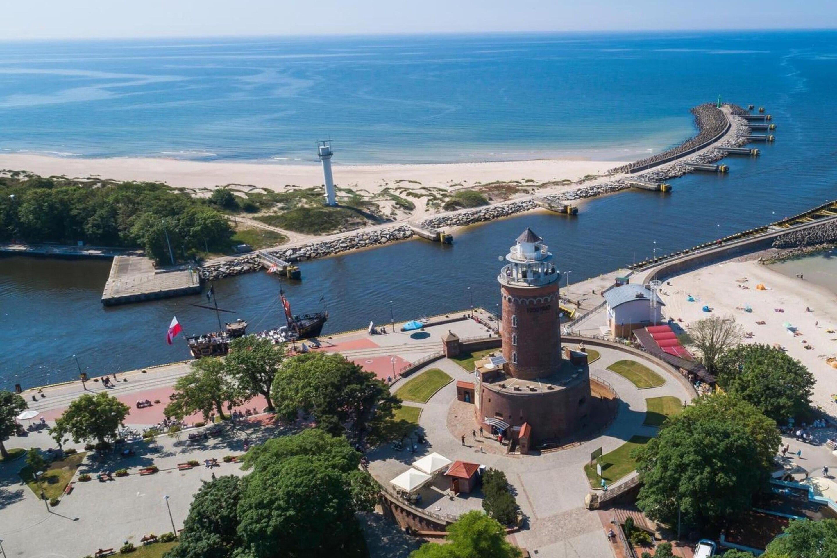 A coastal area with a lighthouse, a pier, and a beach.