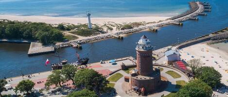 A coastal area with a lighthouse, a pier, and a beach.