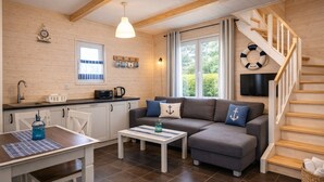 Een gezellig interieur van een blokhut met een keuken, een eetgedeelte en een trap.