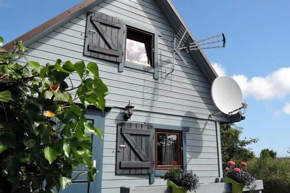 A house with a satellite dish, a wooden door, and a window with shutters. - Holiday Home in a Holiday Park Rewal at 600 m From the sea (Rewal)