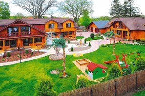 A lodge with multiple wooden cabins, a central courtyard with a fountain, and a playground area. - Comfortable 2-storey Holiday Home, Ustronie Morskie (Ustronie Morskie)