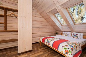 A wooden cabin bedroom with a bed, a wooden bench, and a window overlooking trees. - Comfortable 2-storey Holiday Home, Ustronie Morskie (Ustronie Morskie)