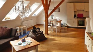 Apartamento estilo loft com área de jantar, cozinha e uma grande janela que proporciona iluminação natural.