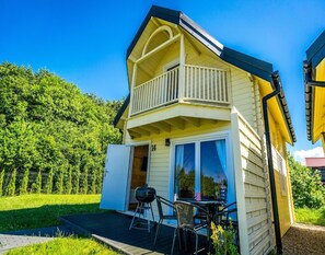 A two-story house with a balcony, a barbecue grill, and a table with chairs on the patio. - Holiday Resort With Pool, Whirlpool, Sauna, Ustronie Morskie (Ustronie Morskie)
