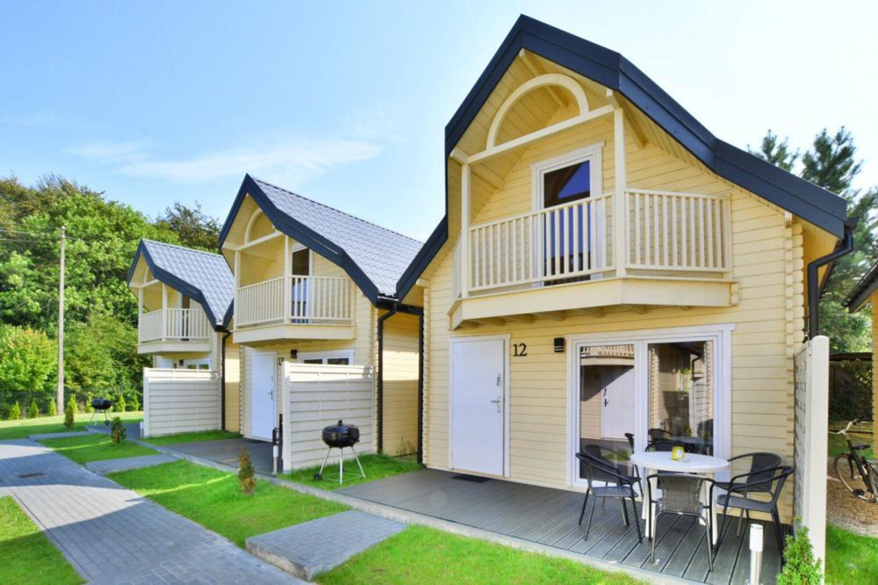 A row of two-story houses with balconies, a barbecue grill, and a patio with outdoor seating.
