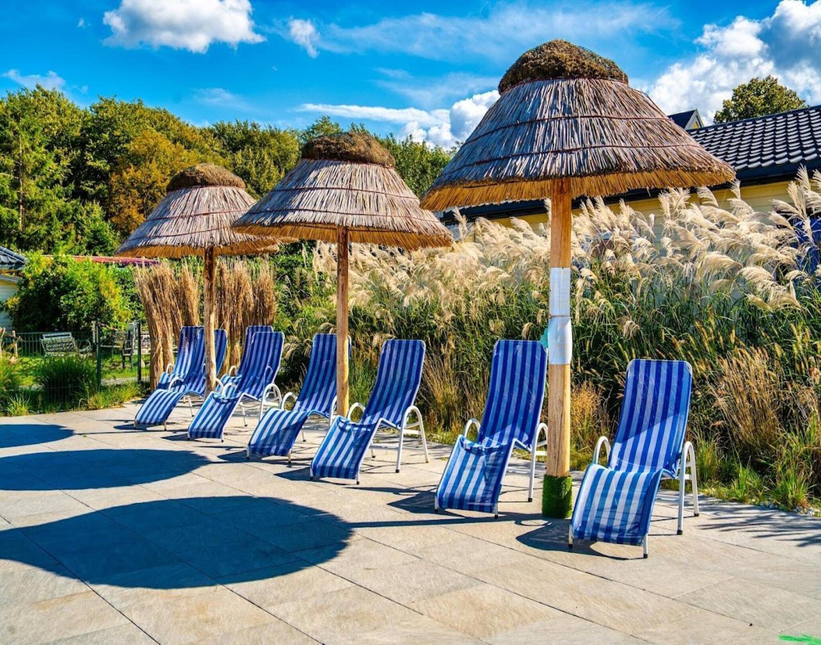A poolside area with striped lounge chairs and thatched umbrellas.