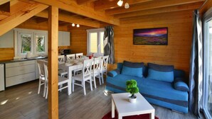 Ein gemütliches Blockhaus-Interieur mit Essbereich, einem blauen Sofa und einem roten Teppich.