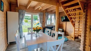 A wooden interior with a dining table, chairs, a staircase, and a television. - Holiday Resort With Pool, Whirlpool, Sauna, Ustronie Morskie (Ustronie Morskie)