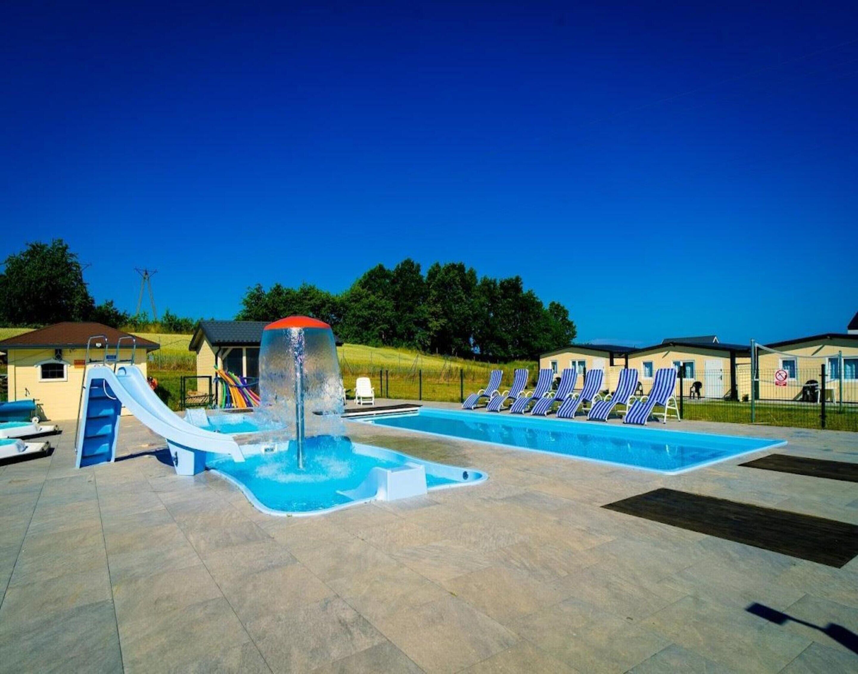 Una piscina con tobogán y sillas de descanso.
