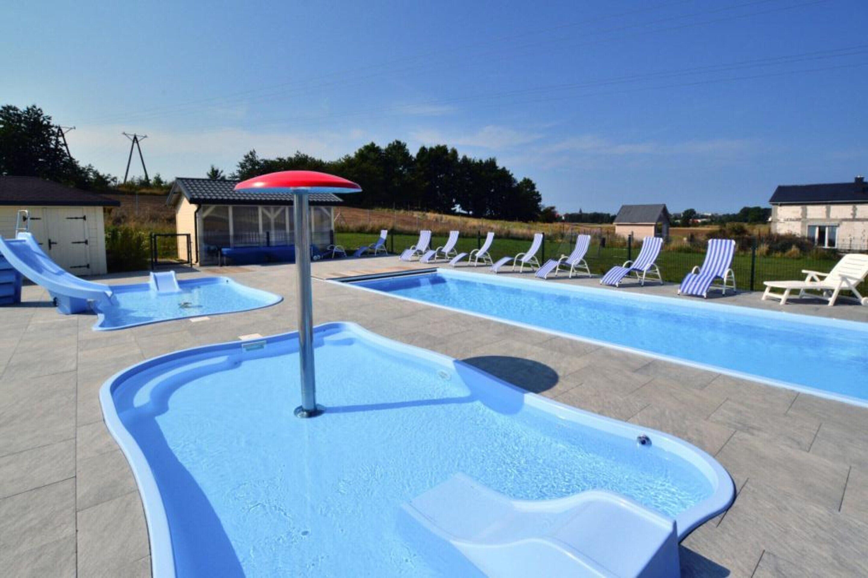 A swimming pool with slides, lounge chairs, and a hot tub.