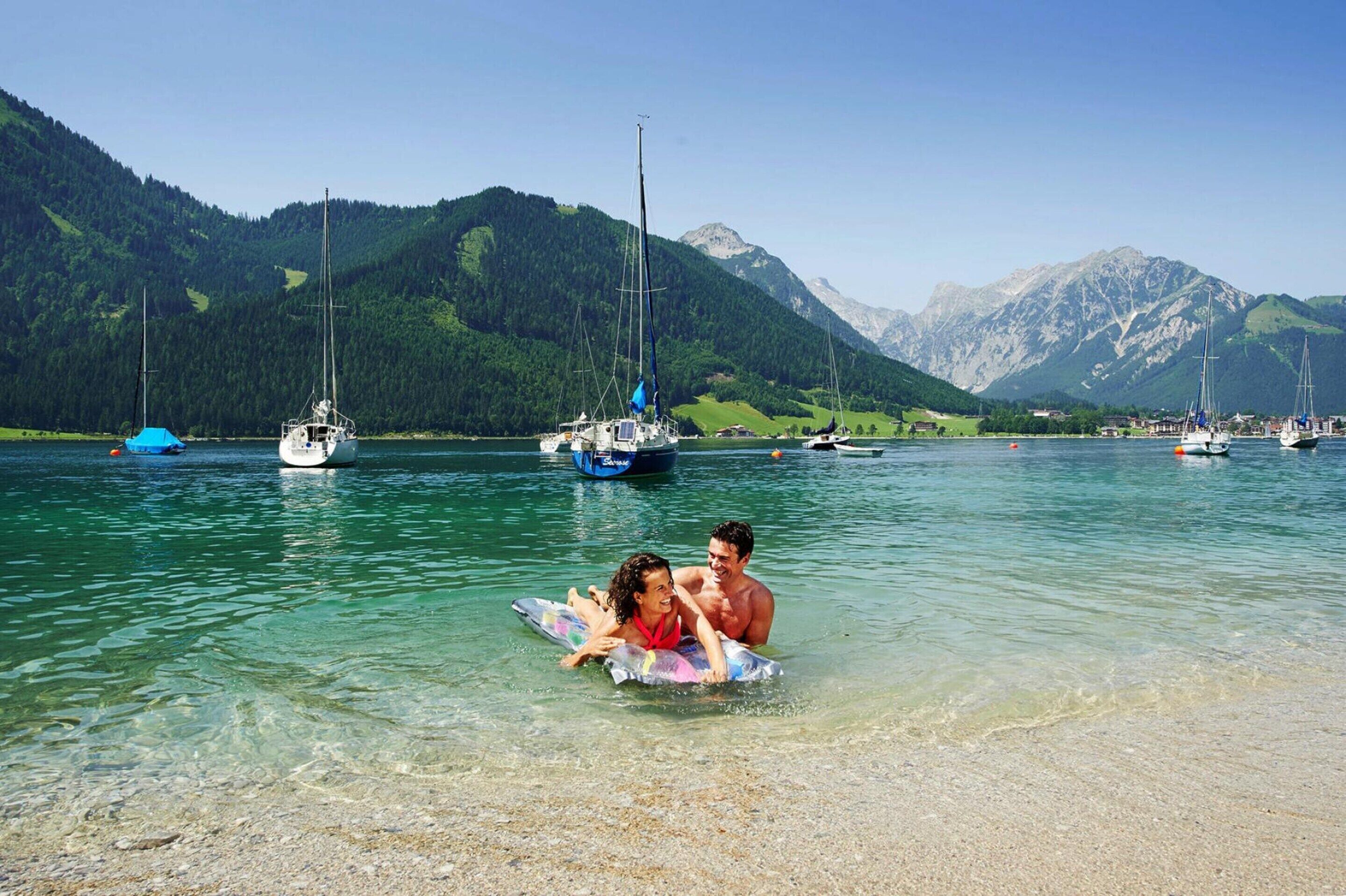A lake with boats and mountains in the background.