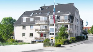 Un edificio a più piani con un balcone al secondo piano, un'asta con delle bandiere e un cartello con la scritta 'Reception'.
