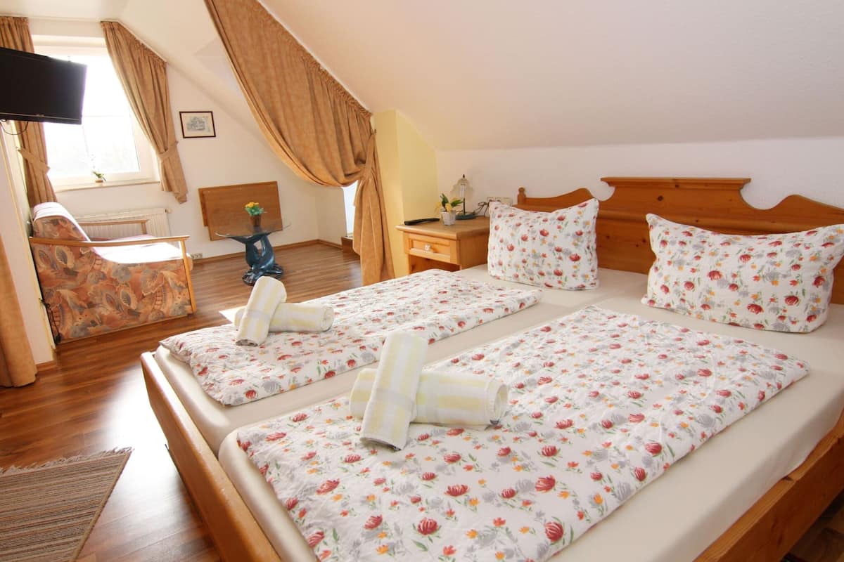 A room with two beds, a television, a small table, and a window with curtains.