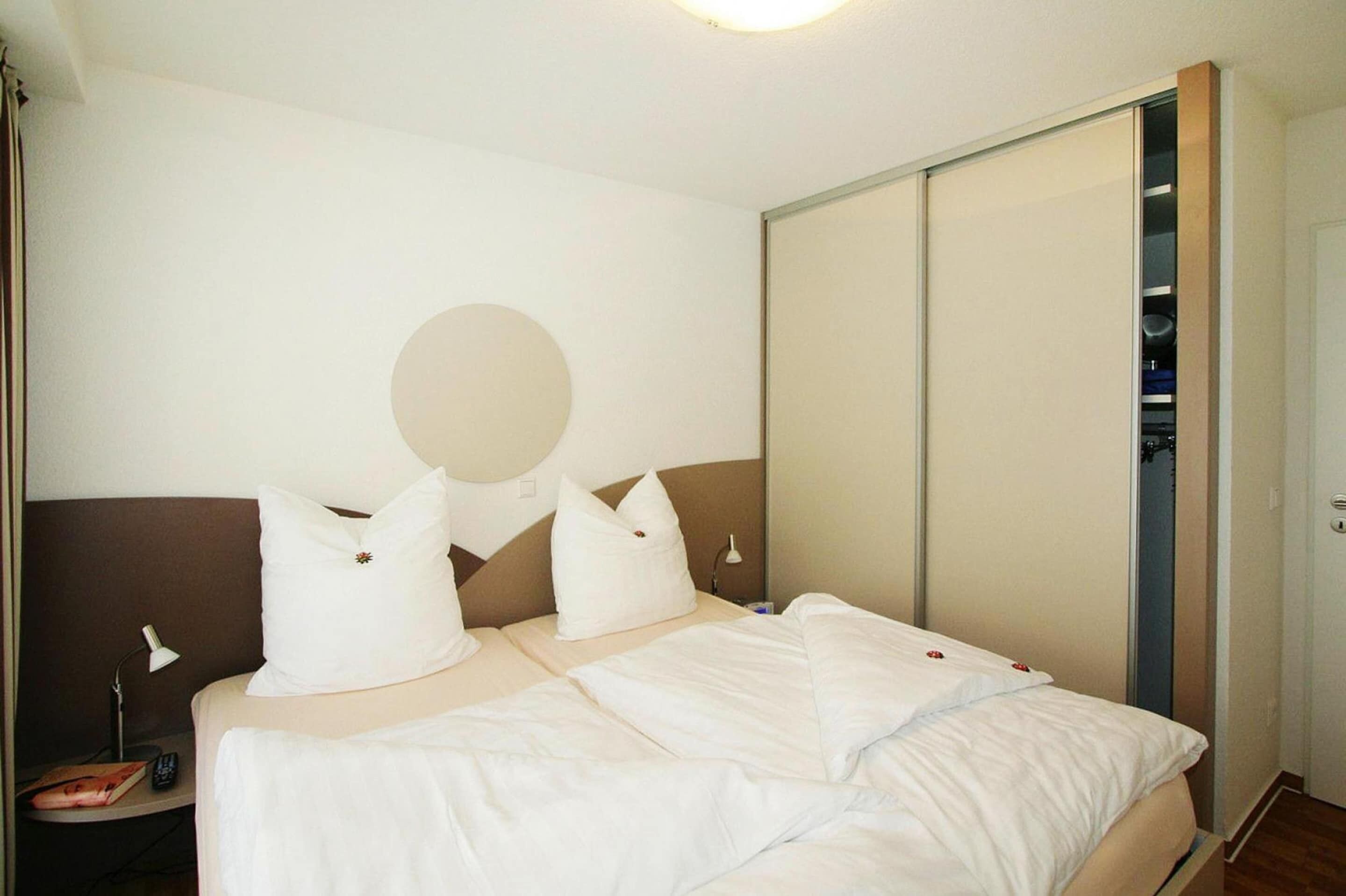 Une chambre d’hôtel avec un lit, une table de chevet, une lampe et une armoire.