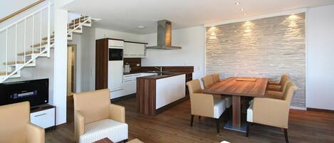 A modern living space with a dining area, kitchen, and a staircase.