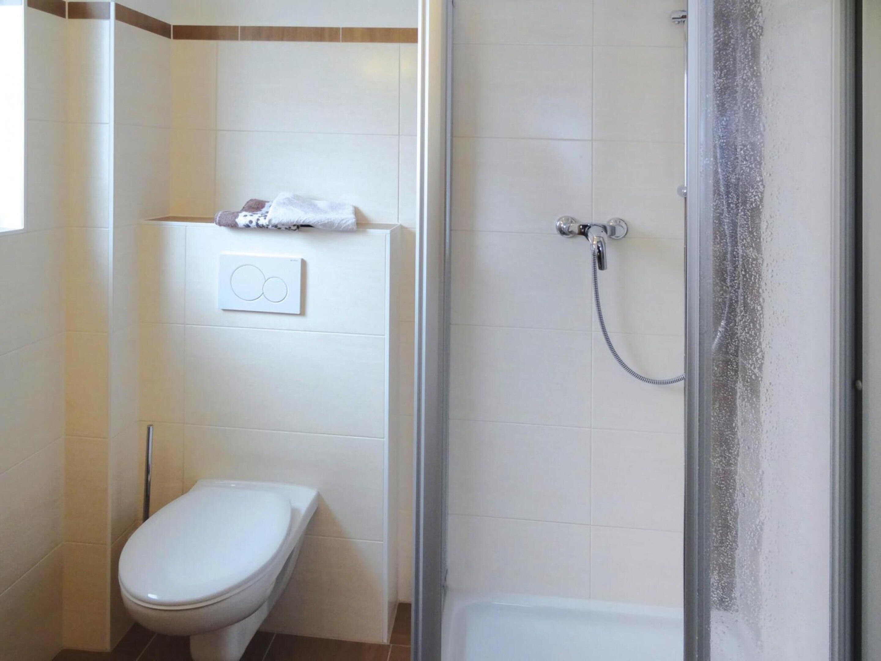 A bathroom with a toilet, a shower, and a towel rack.
