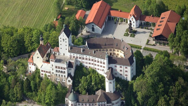 An aerial view of a large, historic building complex with multiple wings and a central tower, surrounded by lush greenery and fields. - Apartment in Aschau at the Lake (Aschau Im Zillertal)