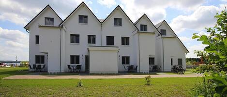 A large, white, multi-story building with a symmetrical design, featuring multiple windows and a central entrance.