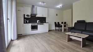 Eine moderne Wohnung mit Küchenzeile, Essbereich und Wohnzimmer mit Sofa und Couchtisch.