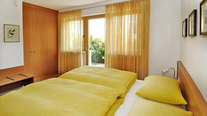 Une chambre d’hôtel avec deux lits, une armoire en bois et une vue sur la verdure environnante.