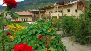 Un bâtiment à deux étages doté de balcons, entouré d’une végétation luxuriante et avec des montagnes en toile de fond.
