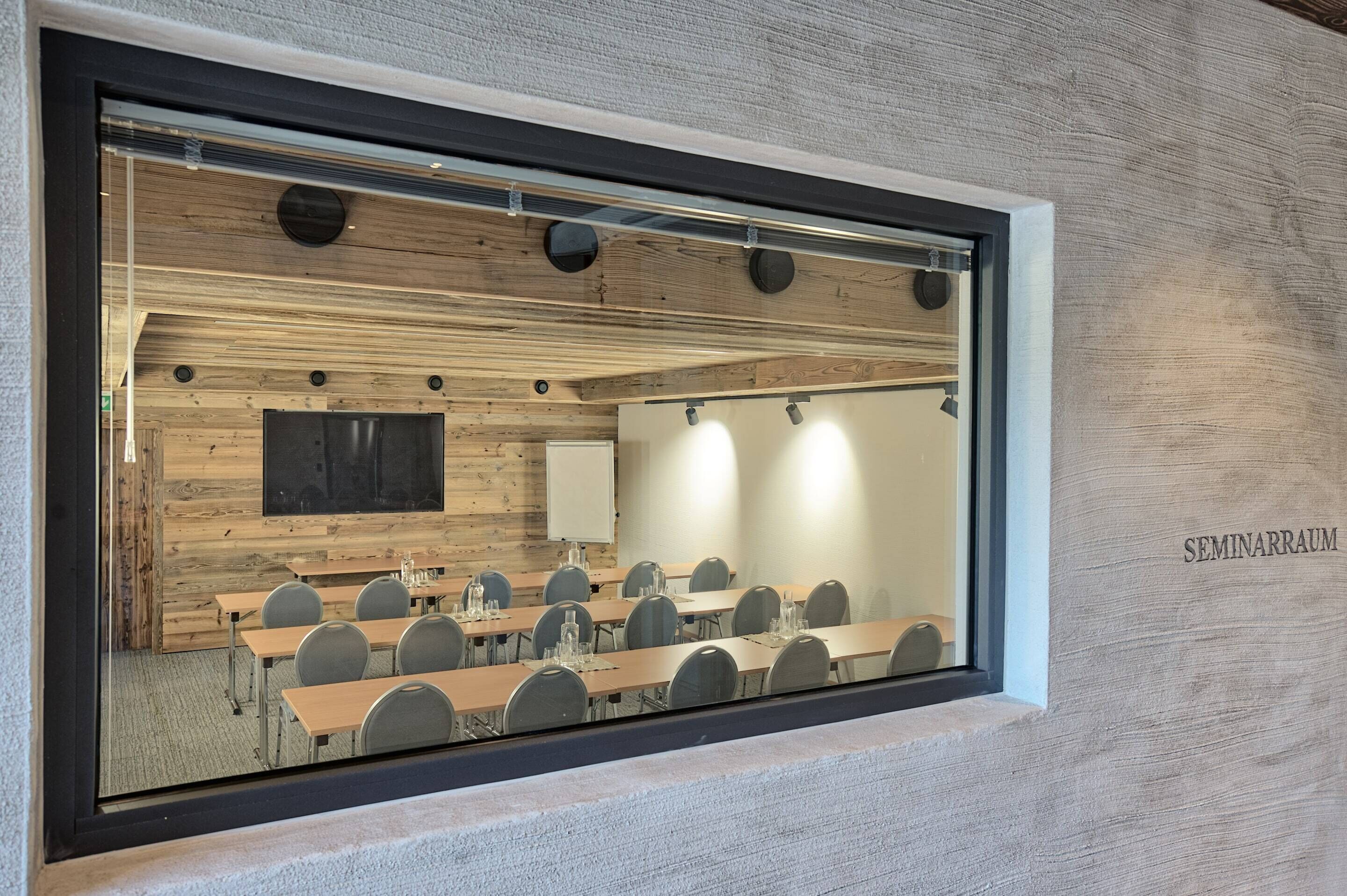 Una sala de conferencias con una larga mesa, sillas, una pizarra y una pantalla de proyector.