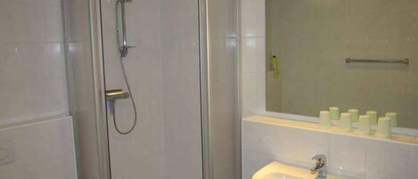 A bathroom with a glass-enclosed shower, a sink, and a mirror above it.