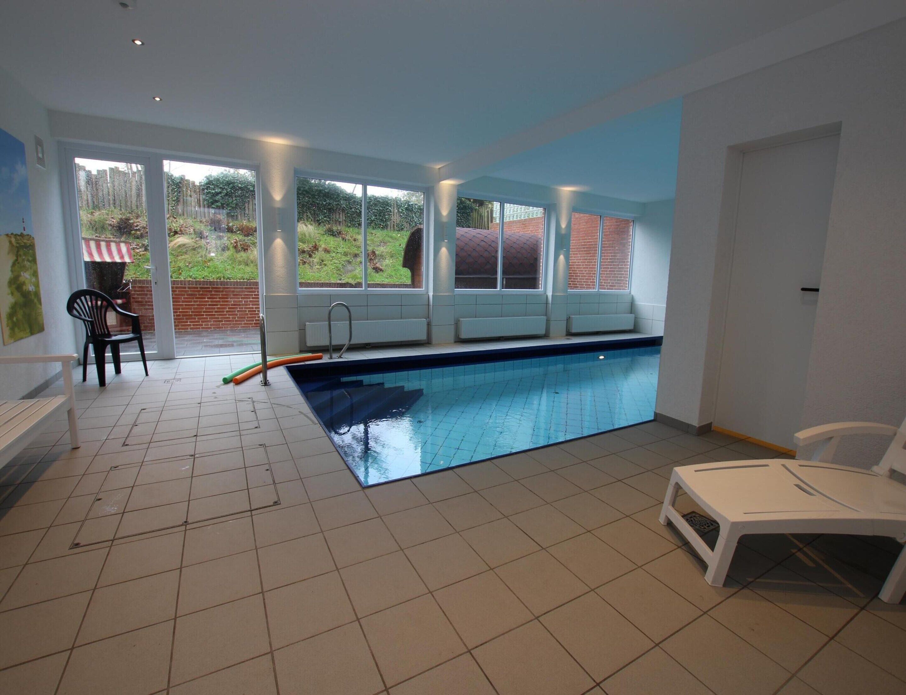 Une piscine intérieure donnant sur un jardin grâce à de grandes baies vitrées.