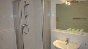 A bathroom with a glass-enclosed shower, a sink, and a mirror above it.